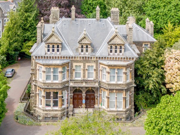 Mansion House is Grade II Listed, and designed in a free classical style. It is arranged over three storeys and basement. The house is constructed from rock-faced Pennant sandstone, with lighter Bath stone dressings under a slate roof with three dormers.
In total, the house comprises c. 16,445 sq ft (1,528 sq m).
Mansion House is set in grounds of c.0.83 acres, and is accessed by two electric gates to the front, with a spacious driveway which circumvents the house.
The rear of the house has experienced various additions, including a ramp to the rear door and metal escape, and is partially fenced off. Improving the rear of the house may include the potential to extend, subject to securing the necessary planning consents.
The trees and foliage to the rear and side of the house has become overgrown, and clearance may provide more space for landscaping and parking.
To the rear is a detached single storey garage with separate access onto Gordon Road. This offers future development potential, subject to planning.